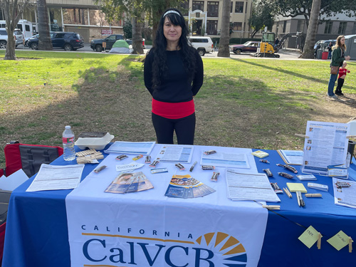 A woman standing behind a CalVCB table